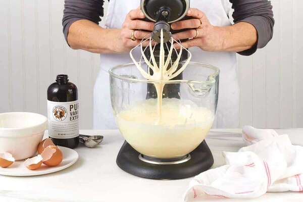 اضافه کردن تخم‌مرغ به مخلوط پودر قند و روغن جامد در طرز تهیه شیرینی کشمشی